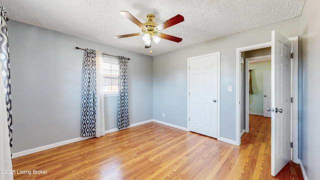 unfurnished bedroom featuring baseboards, ceiling fan, a textured ceiling, and light wood finished floors