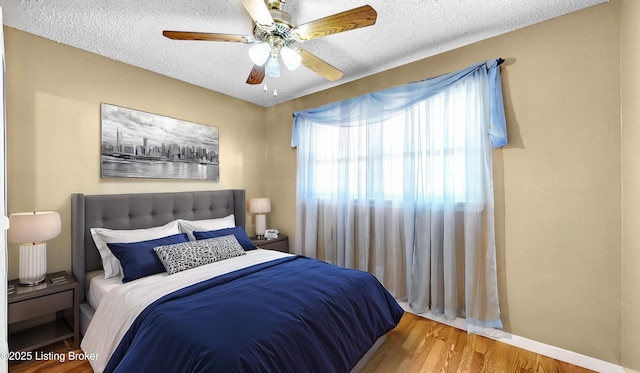 bedroom with a textured ceiling, wood finished floors, and a ceiling fan