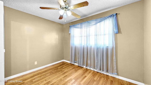 empty room with a ceiling fan, a textured ceiling, baseboards, and wood finished floors