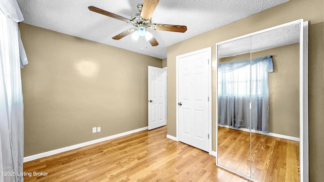 unfurnished bedroom with a textured ceiling, ceiling fan, light wood-type flooring, and baseboards