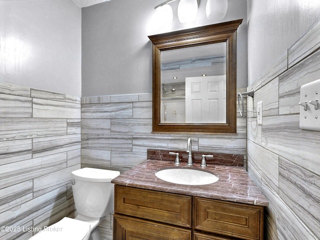 bathroom featuring tile walls, vanity, and toilet