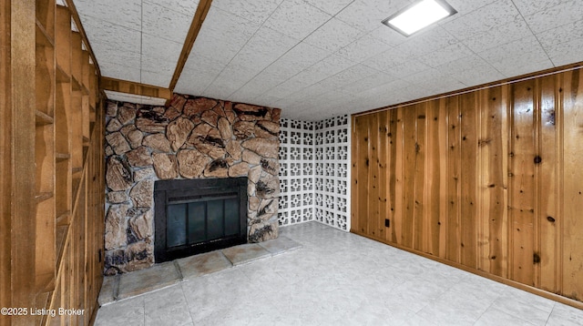 unfurnished living room featuring wood walls and a stone fireplace