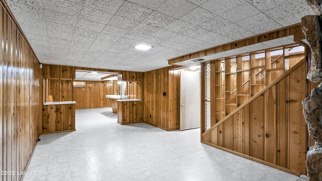 finished basement with wood walls, visible vents, and tile patterned floors