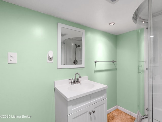 full bath with vanity, a shower with door, and baseboards