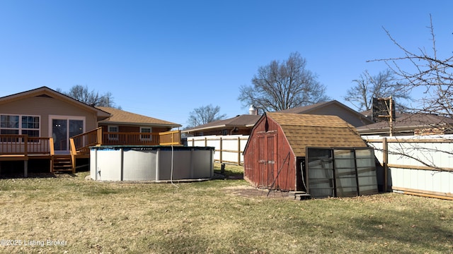 view of yard with an outbuilding, a storage unit, fence, a deck, and an outdoor pool