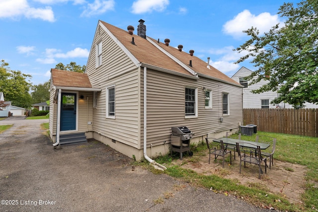 view of side of property with entry steps, a patio, outdoor dining area, central air condition unit, and fence