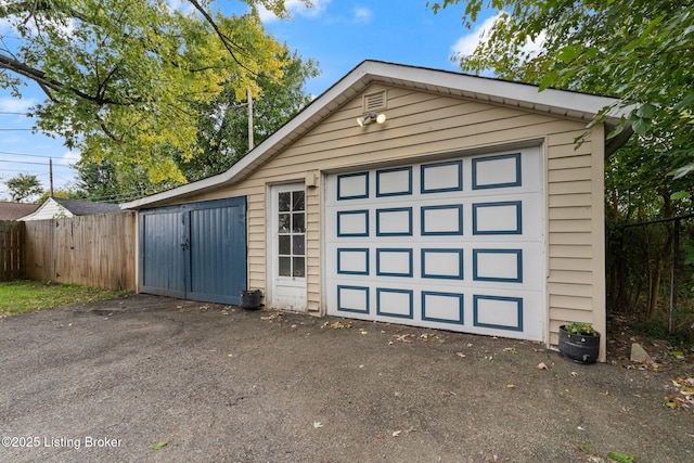 view of outbuilding featuring driveway, an outdoor structure, and fence