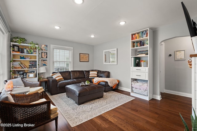 living area with arched walkways, dark wood finished floors, baseboards, and recessed lighting