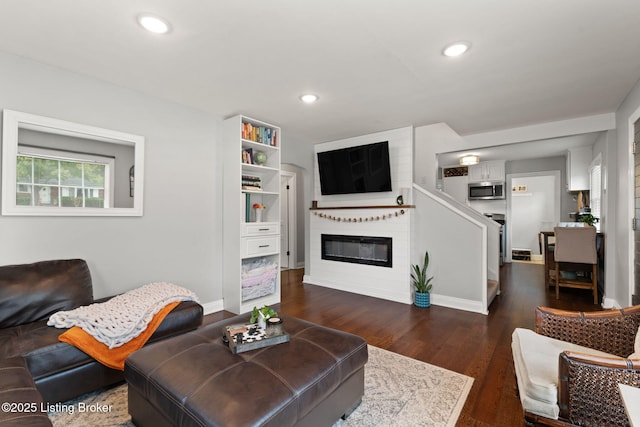 living room with baseboards, a glass covered fireplace, dark wood finished floors, and recessed lighting