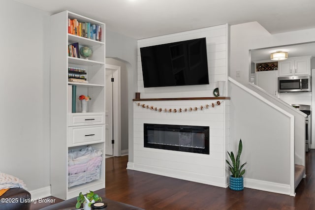 living area featuring dark wood-style floors, a fireplace, and baseboards