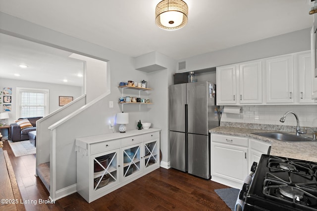 kitchen featuring light countertops, freestanding refrigerator, gas stove, white cabinets, and a sink