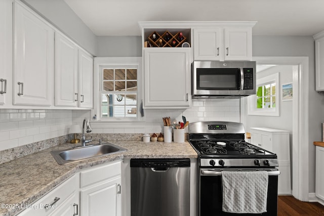 kitchen featuring stainless steel appliances, white cabinetry, and a sink