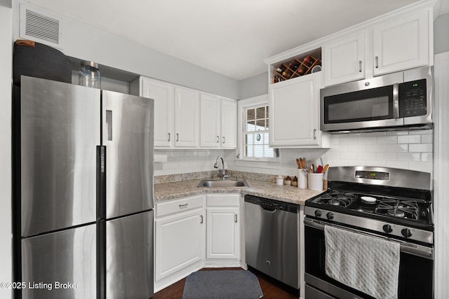 kitchen with appliances with stainless steel finishes, white cabinets, light countertops, and visible vents