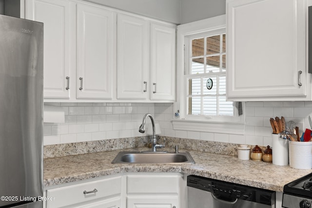 kitchen with stainless steel appliances, tasteful backsplash, light countertops, white cabinets, and a sink