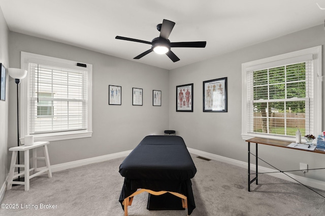 living area with visible vents, baseboards, ceiling fan, and light colored carpet