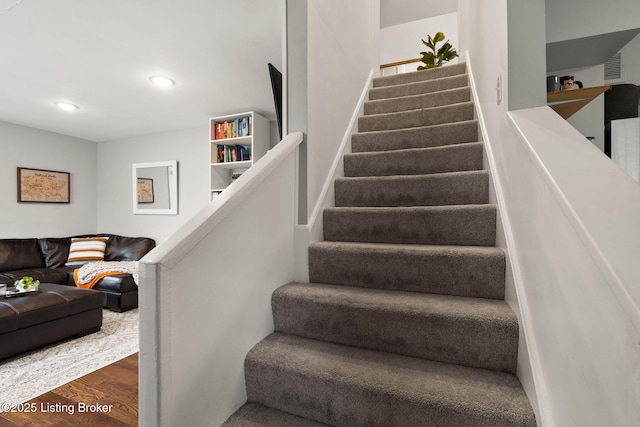 stairway featuring wood finished floors and recessed lighting