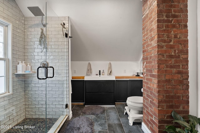 bathroom featuring vaulted ceiling, a sink, toilet, and a healthy amount of sunlight