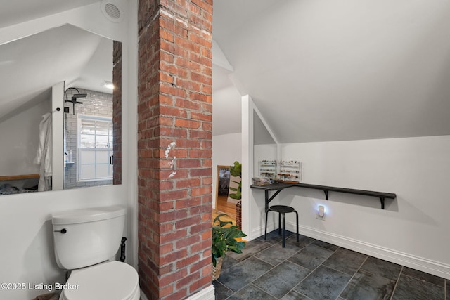 bathroom featuring lofted ceiling, toilet, brick wall, visible vents, and baseboards