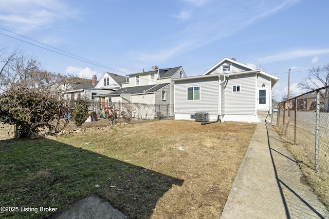 rear view of property with central AC unit, a lawn, and fence