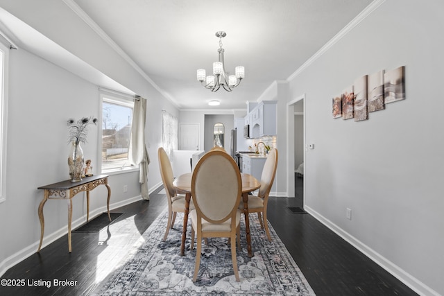 dining room featuring a chandelier, ornamental molding, dark wood finished floors, and baseboards