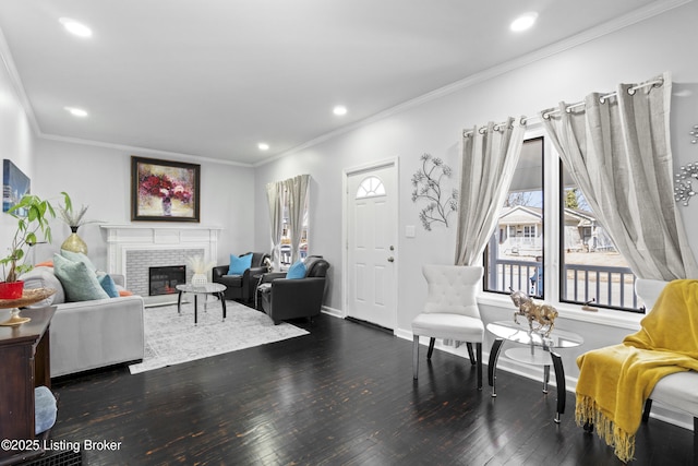 living room with dark wood-style floors, a brick fireplace, crown molding, and recessed lighting