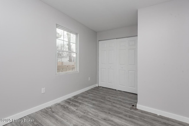 unfurnished bedroom featuring a closet, baseboards, and wood finished floors