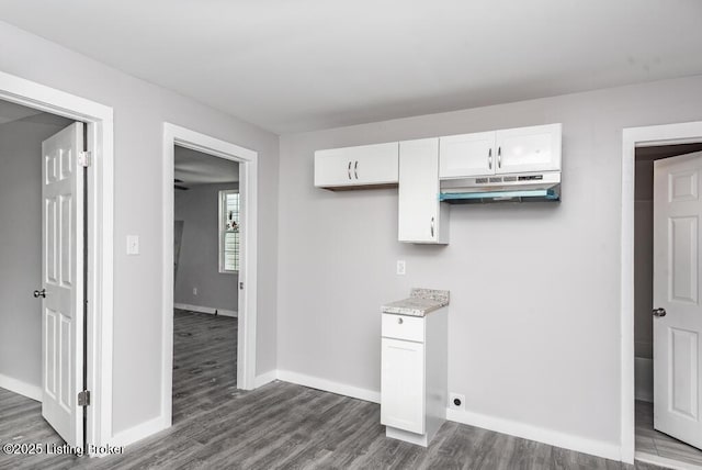 kitchen featuring dark wood-type flooring, light countertops, white cabinets, and under cabinet range hood