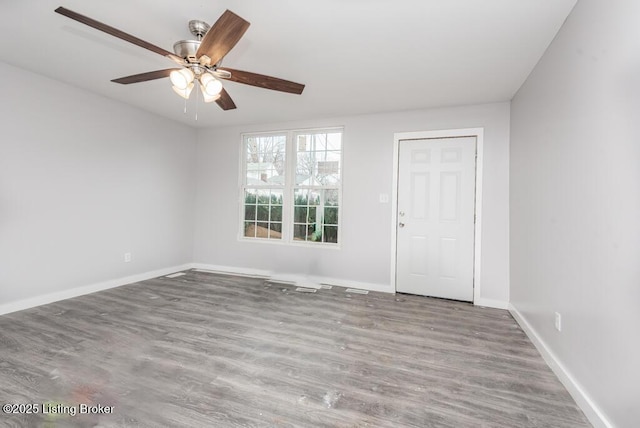 empty room with a ceiling fan, light wood-style flooring, and baseboards