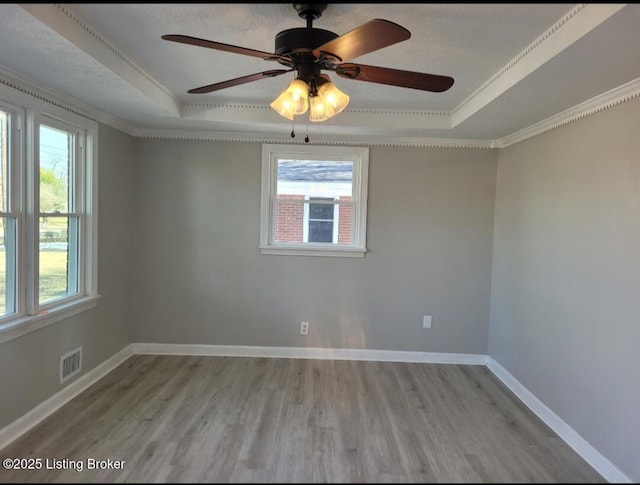 unfurnished room featuring plenty of natural light, visible vents, and a raised ceiling