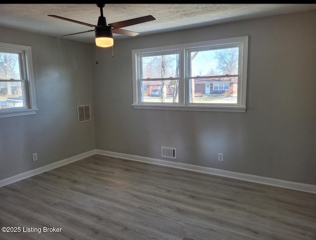 spare room with a textured ceiling, visible vents, and baseboards