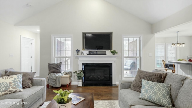 living room with an inviting chandelier, a fireplace with flush hearth, vaulted ceiling, and wood finished floors