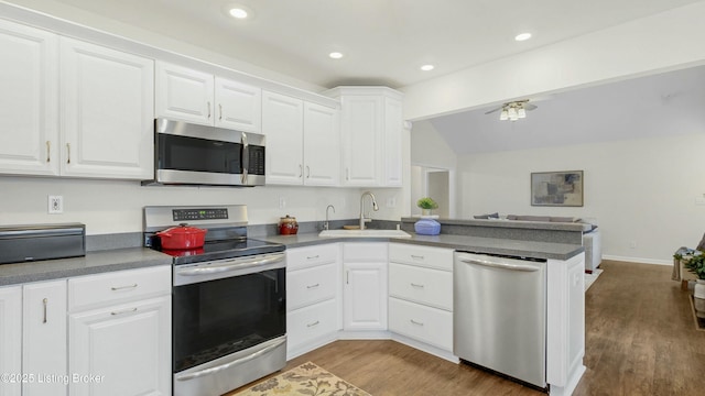 kitchen featuring open floor plan, stainless steel appliances, a sink, and white cabinets