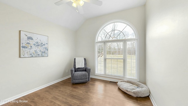 sitting room featuring wood finished floors, visible vents, baseboards, vaulted ceiling, and a ceiling fan