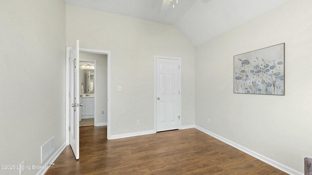 unfurnished bedroom featuring vaulted ceiling, dark wood-type flooring, visible vents, and baseboards