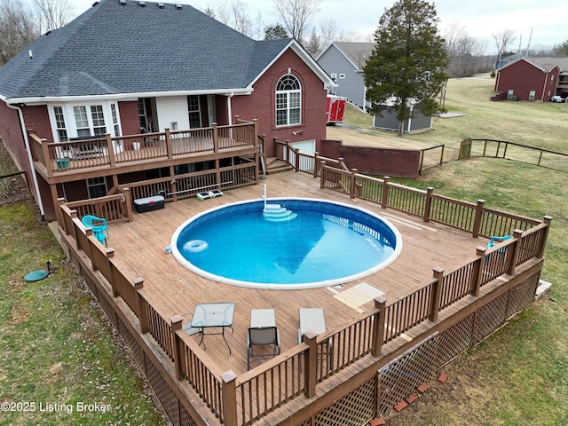 view of swimming pool with a deck, a yard, fence, and a fenced in pool