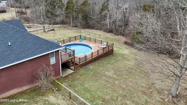 view of swimming pool with fence, a lawn, and a wooden deck