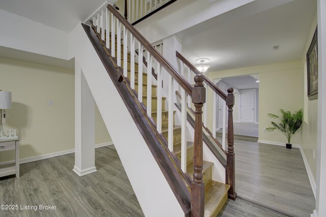 staircase featuring baseboards and wood finished floors