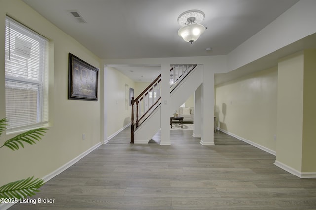 below grade area featuring stairs, visible vents, light wood-style flooring, and baseboards