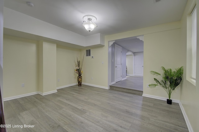 empty room featuring light wood-type flooring, visible vents, and baseboards