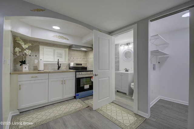 kitchen with light countertops, white cabinets, a sink, and stainless steel electric stove