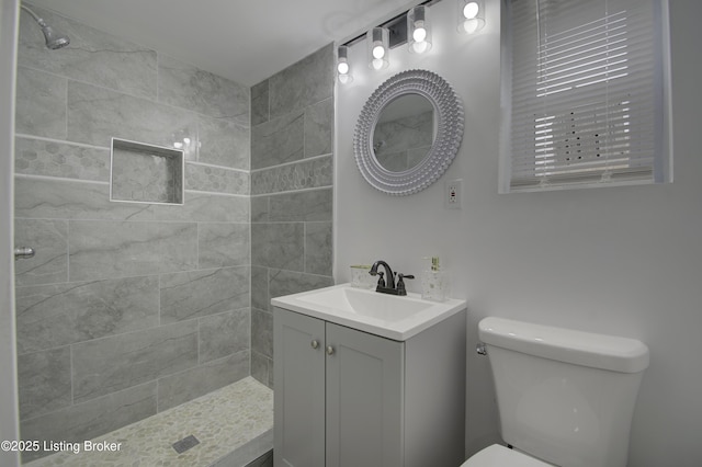 full bath with a tile shower, vanity, and toilet