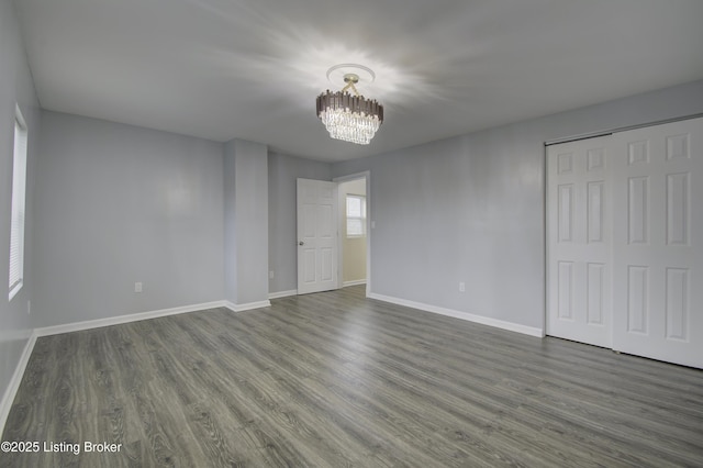 interior space featuring dark wood-style floors, a chandelier, a closet, and baseboards