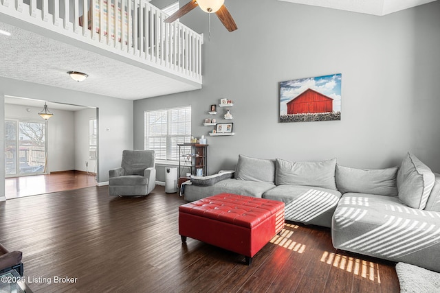 living room with a textured ceiling, wood finished floors, a towering ceiling, and baseboards