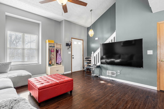 living room with stairs, a textured ceiling, baseboards, and wood finished floors