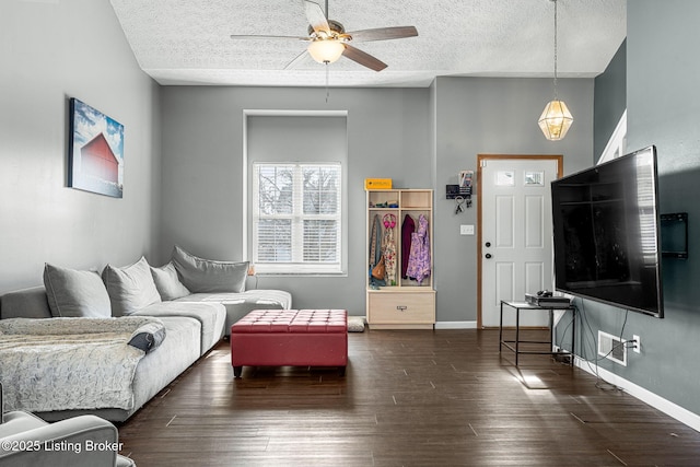 living room featuring ceiling fan, a textured ceiling, baseboards, and wood finished floors