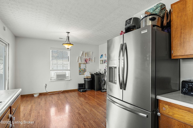 kitchen with light countertops, brown cabinetry, wood finished floors, and stainless steel fridge with ice dispenser