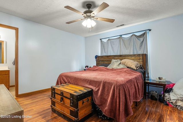 bedroom with visible vents, a ceiling fan, a textured ceiling, wood finished floors, and baseboards