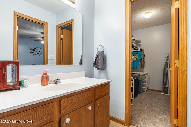 bathroom featuring a ceiling fan, baseboards, a textured ceiling, and vanity