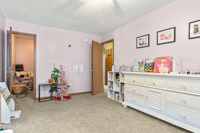 playroom with light carpet, ceiling fan, a textured ceiling, and baseboards