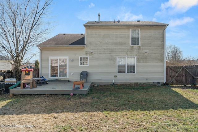 back of property featuring a deck, a lawn, and fence